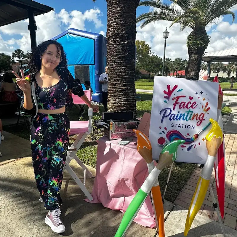 Face painting in Miami: a Fantasy Entertainments artist at her colorful face painting station during a community park event.