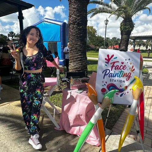 Face painting in Miami: a Fantasy Entertainments artist at her colorful face painting station during a community park event.