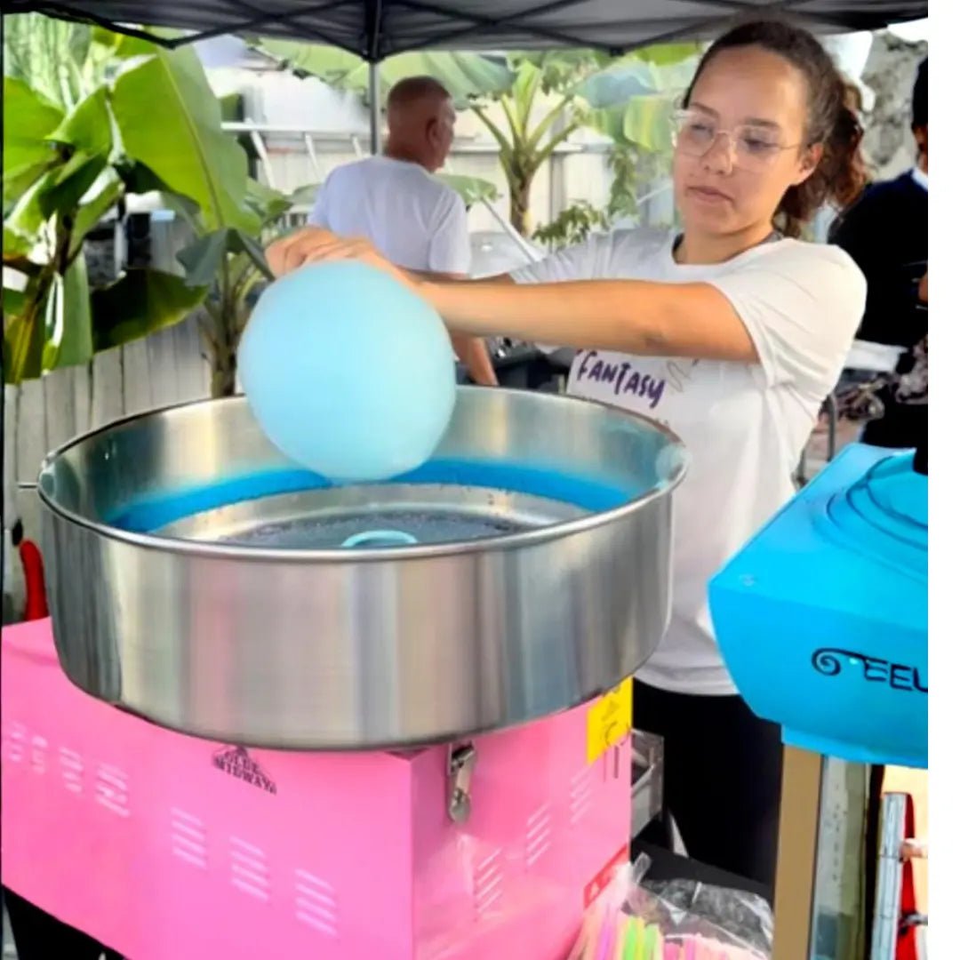 Cotton candy machine rental in Miami: a Fantasy Entertainments attendant spinning fluffy blue cotton candy at an outdoor event.