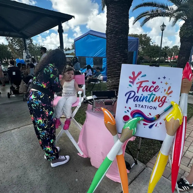 Fantasy Entertainments face painter at work: a little girl gets her face painted at a busy Miami community park event.