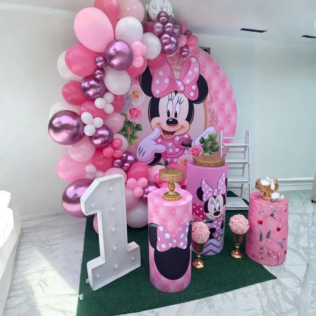First birthday decoration setup with Minnie Mouse backdrop, pink balloon garland arch, pedestals and marquee number one in Miami.