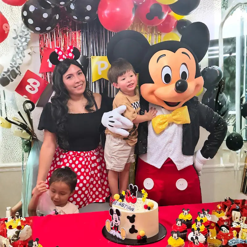 Mickey Mouse character holding the birthday boy while the host poses with the family at a Mickey themed birthday party in Miami.