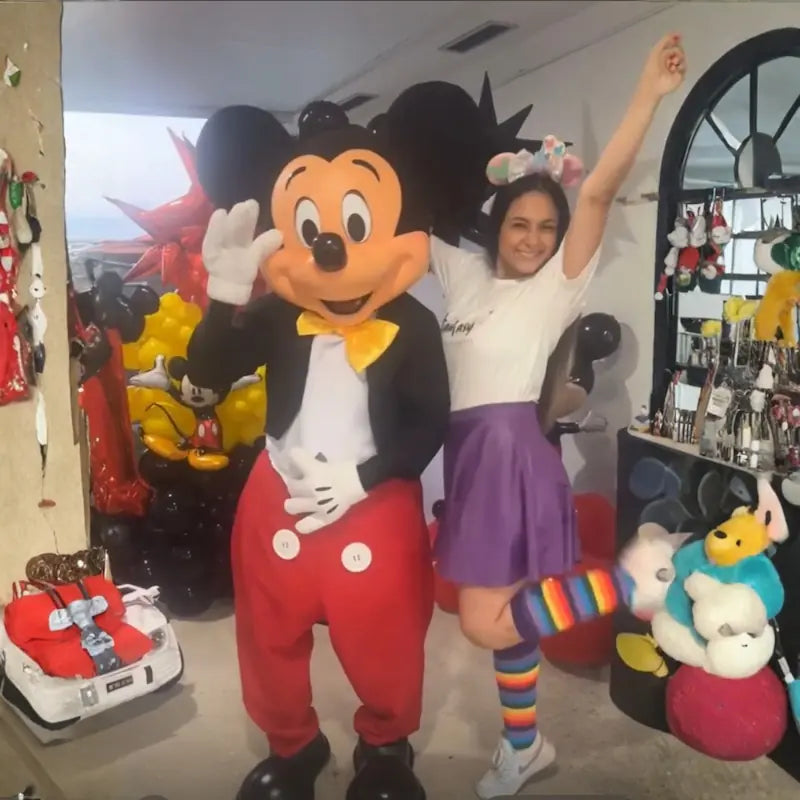 Mickey Mouse mascot waving beside a cheering party host with mouse ears headband, duo entertainment for Miami birthday parties.