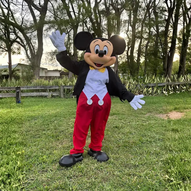 Classic Mickey Mouse character waving hello on a backyard lawn, mouse mascot rental for birthday parties in Miami.