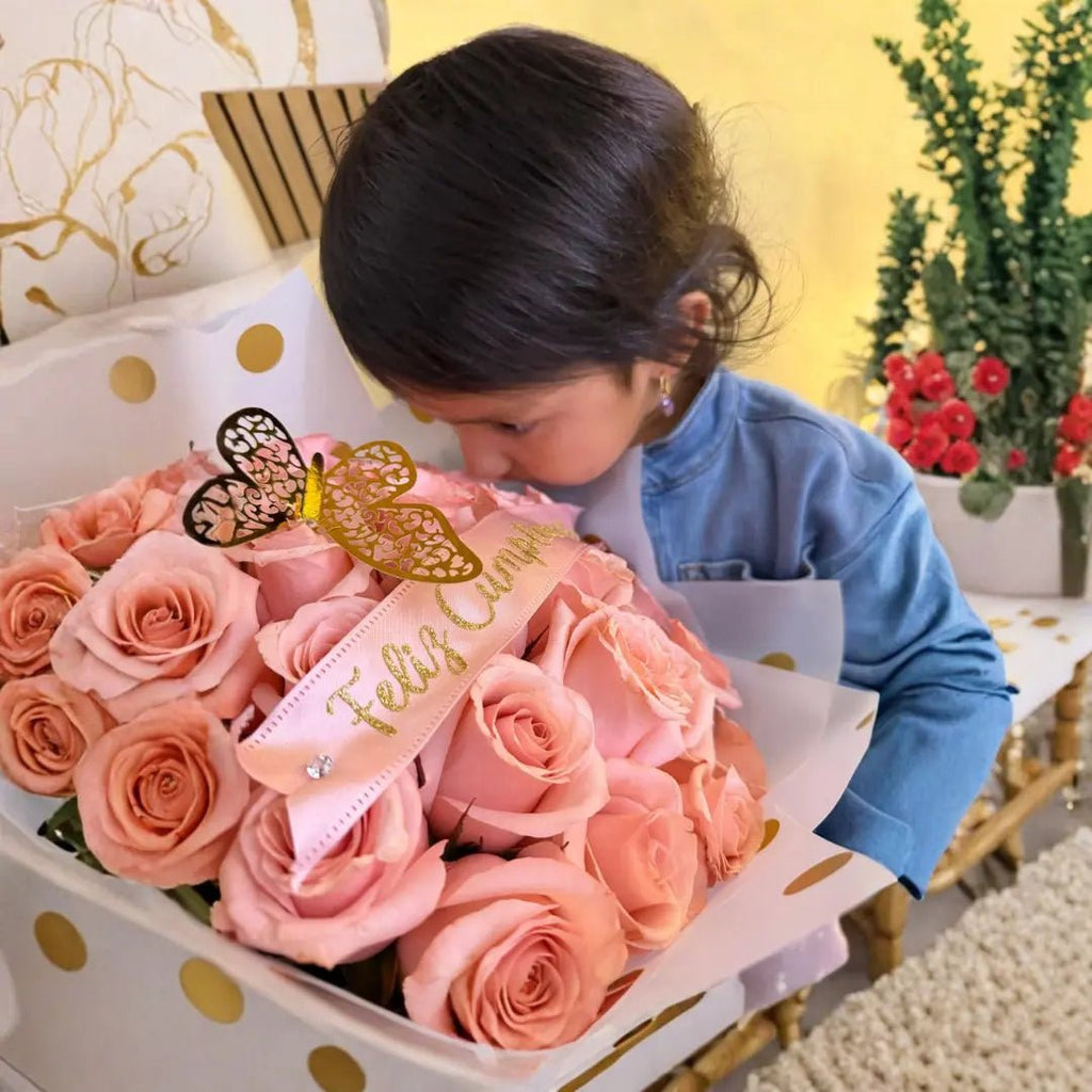 Little girl smelling a pink rose bouquet with a Feliz Cumple ribbon, a birthday surprise gift from Loli the Bunny in Miami.