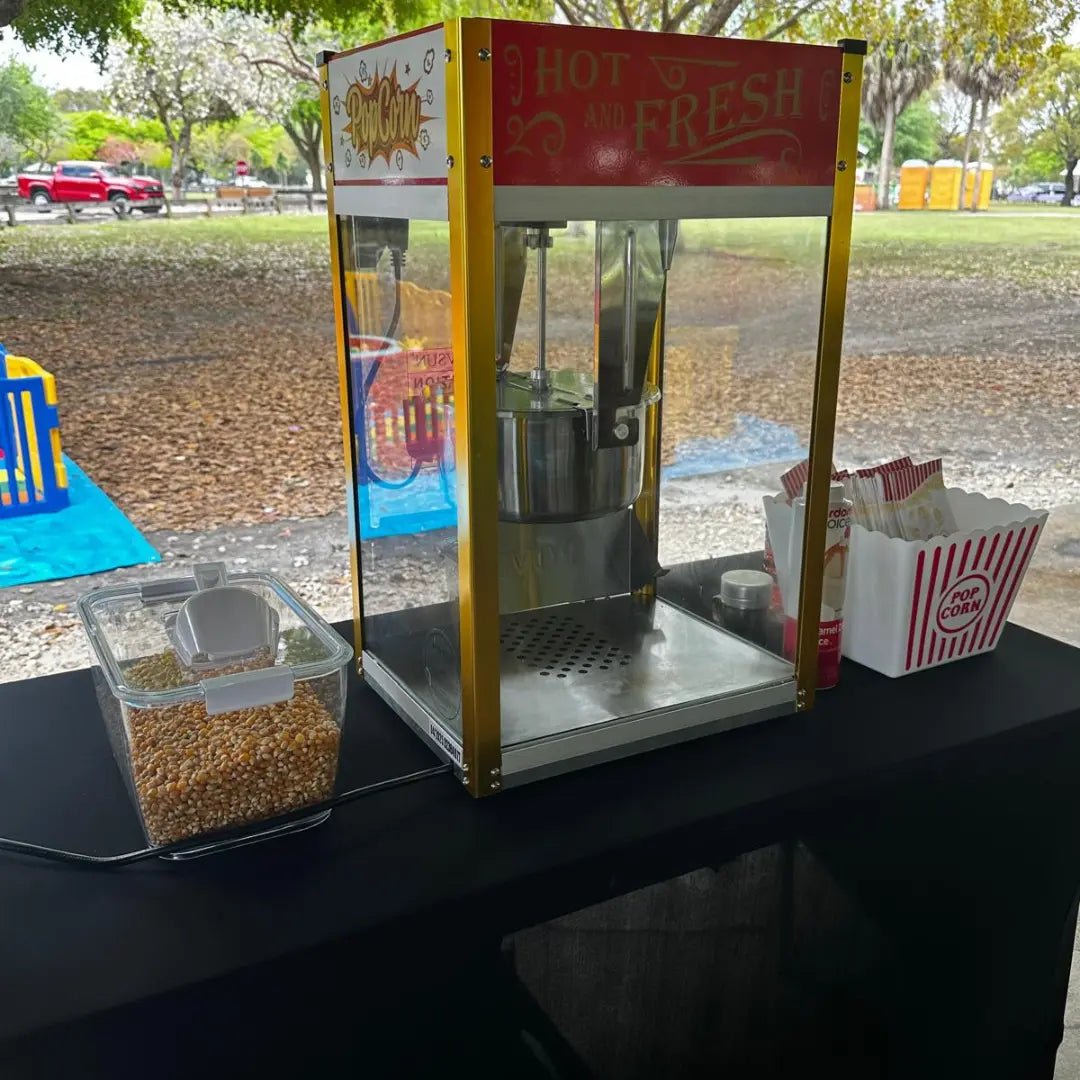 Popcorn machine rental in Miami: a Fantasy Entertainments fresh popcorn station with striped boxes at an outdoor park event.