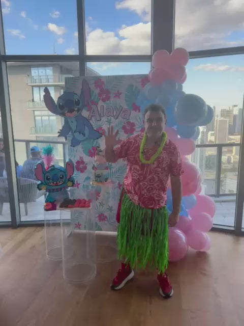 Luau party entertainer in hula skirt waving at a Stitch themed tropical birthday party in a Miami high-rise condo with skyline views.
